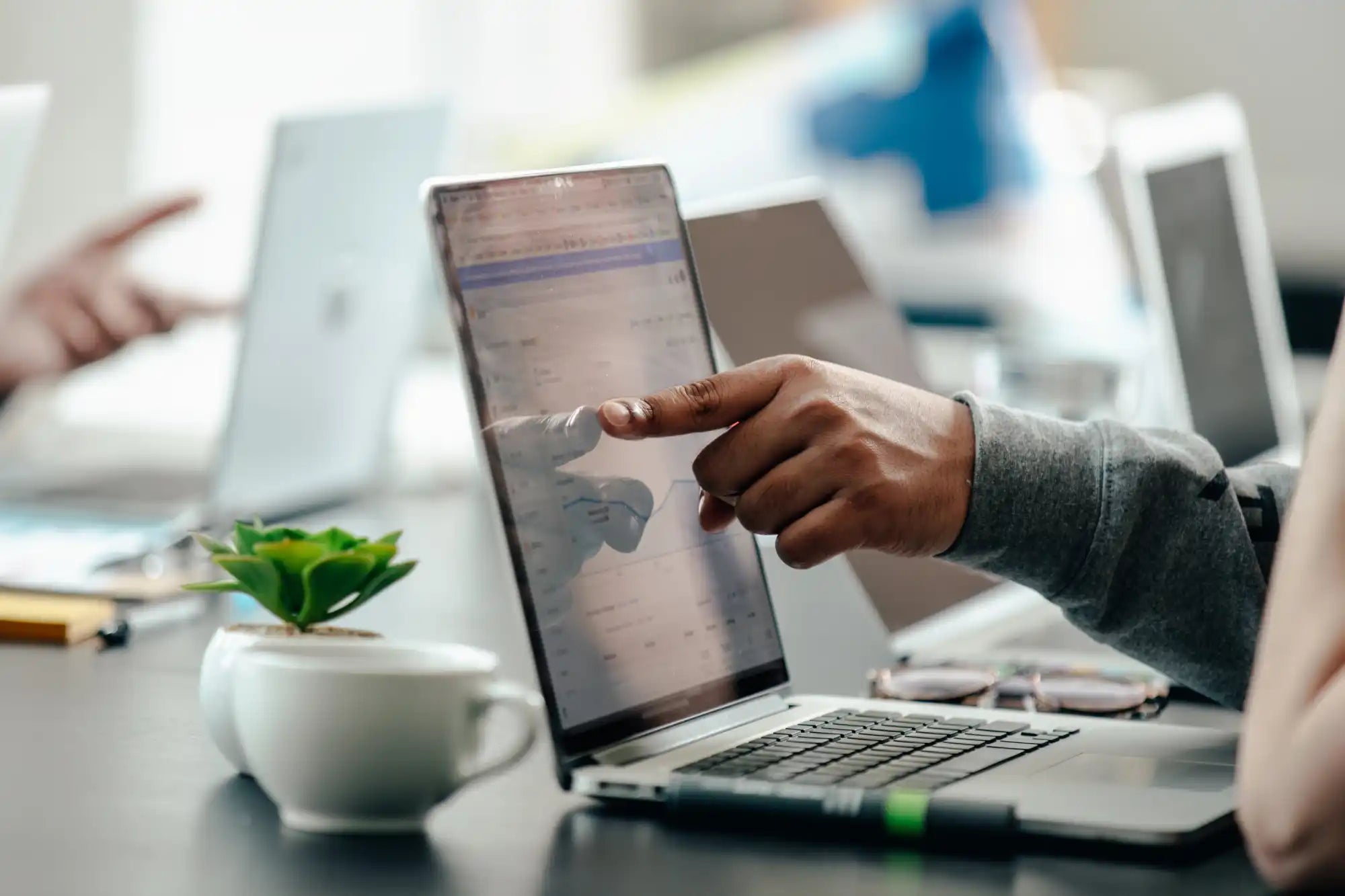 Open laptop with finger pointing at screen.